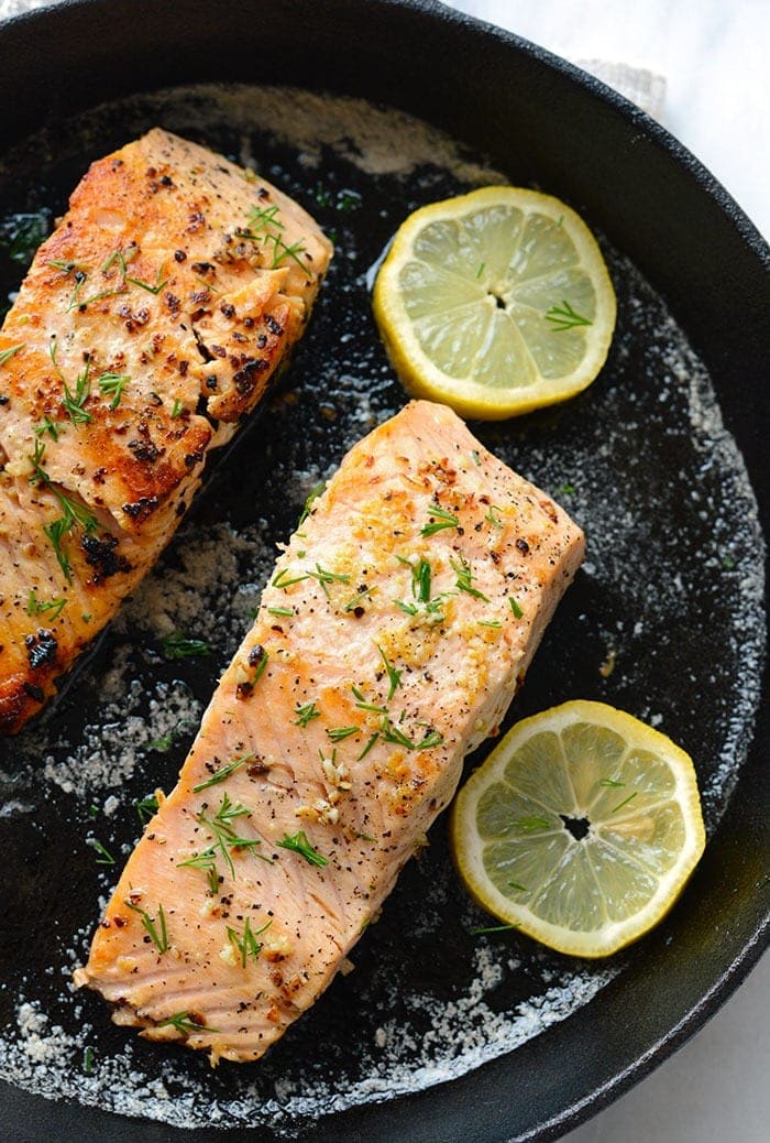 pan seared salmon with lemon in cast iron pan.