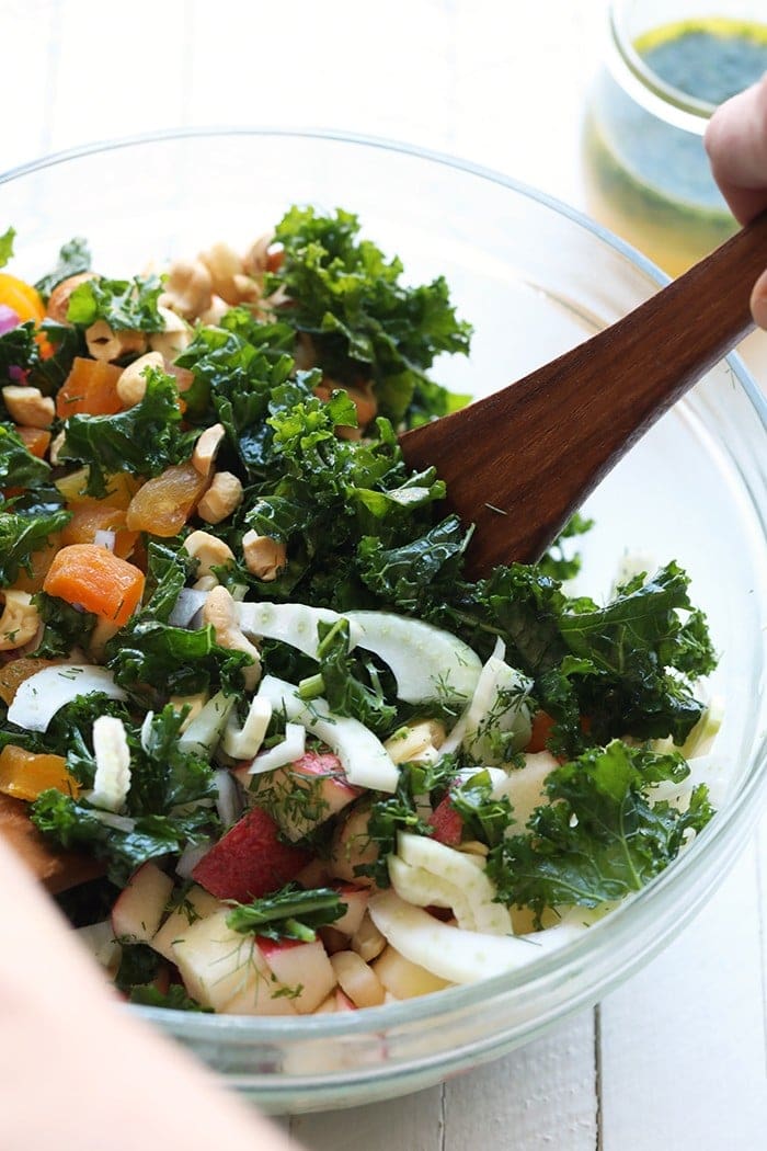 Mixing the massaged kale salad in a bowl. 