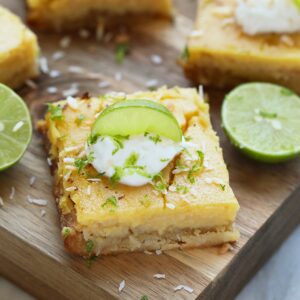 A cutting board with lime wedges and sour cream on it, perfect for making key lime pie.