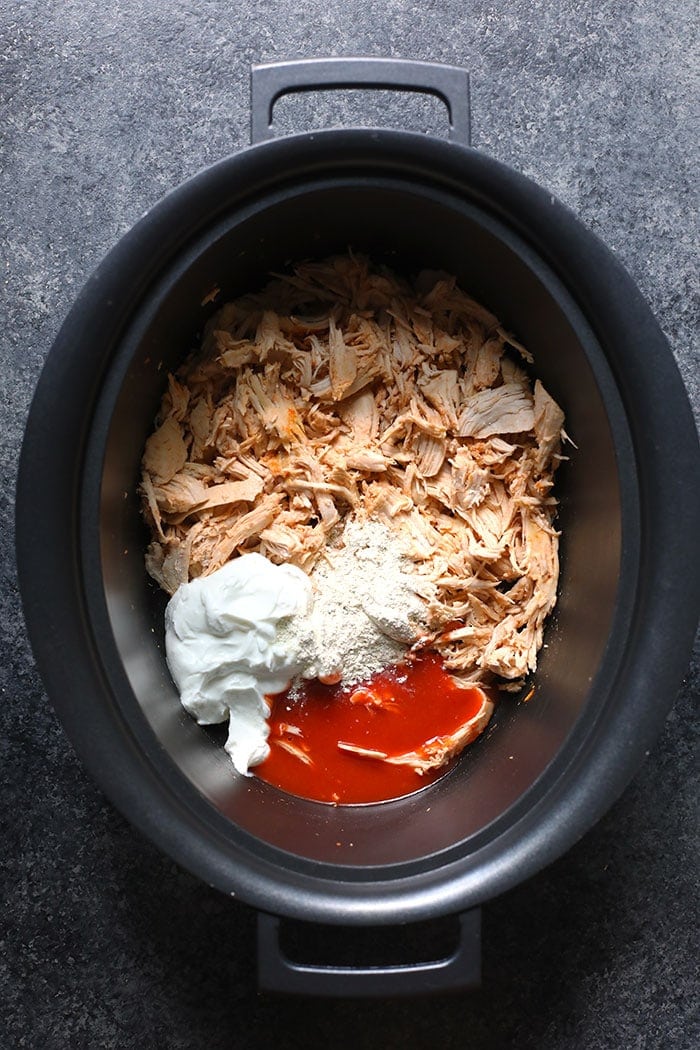 Ingredients for buffalo chicken dip on a slow cooker