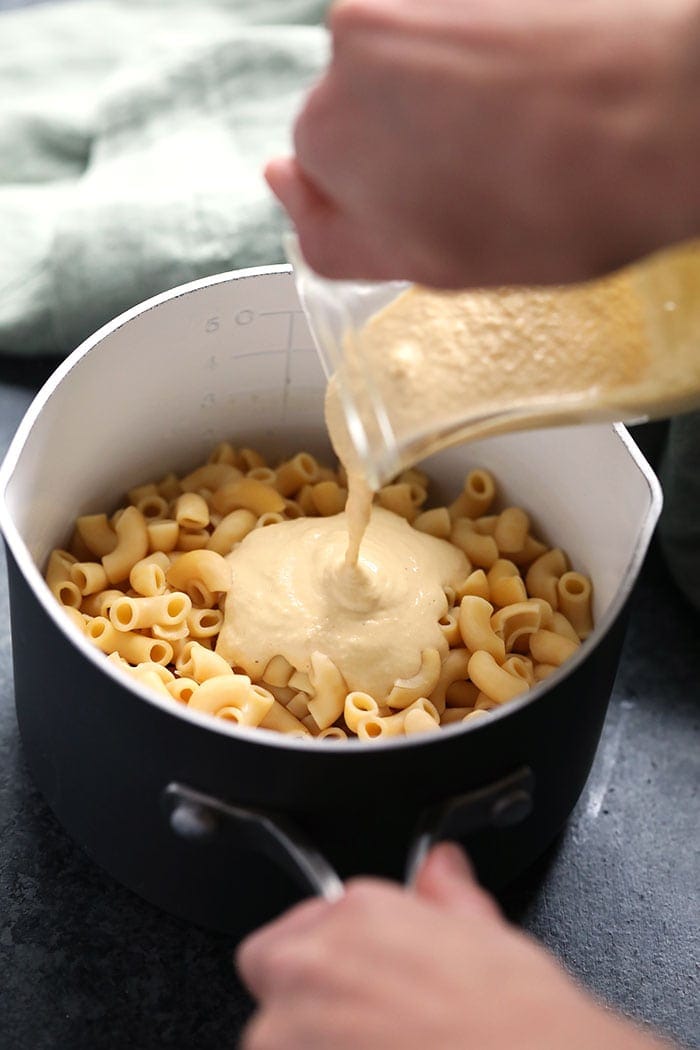 vegan mac and cheese sauce being poured over noodles