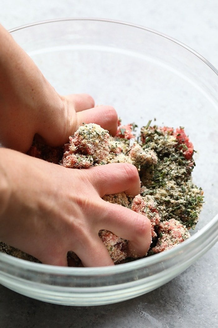 Mixing meatballs in a large glass bowl