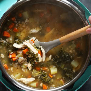 A person pouring leftover turkey soup into a pot.