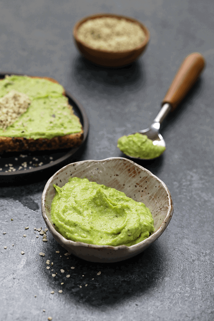 A small bowl and spoon with avocado spread in them