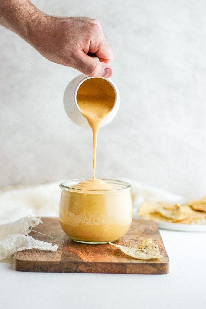 pouring vegan cheese sauce into jar.