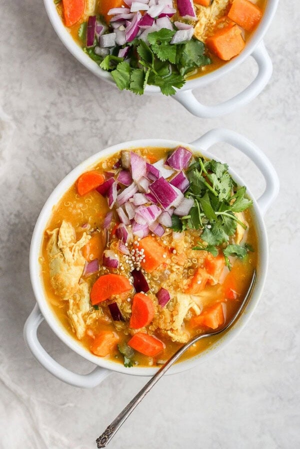 Two bowls of curry chicken soup with carrots and onions.