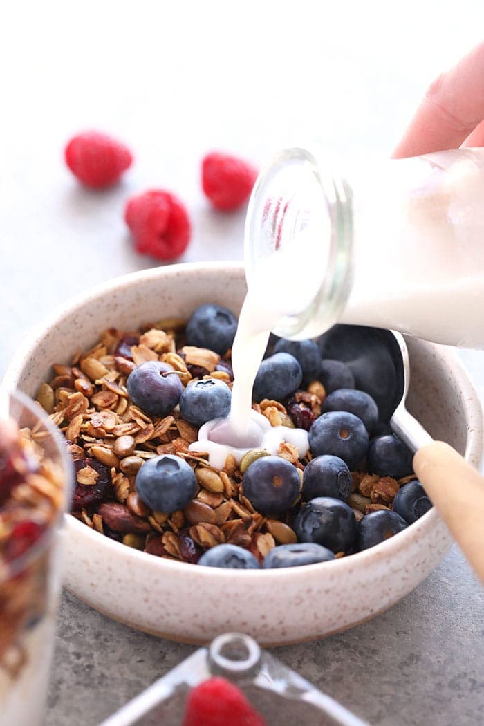 Granola in a bowl with milk and blueberries.