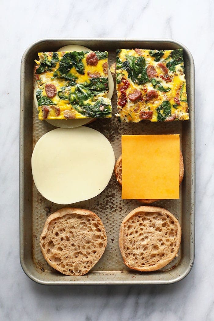 assembling make ahead freezer breakfast sandwiches on a sheet pan.