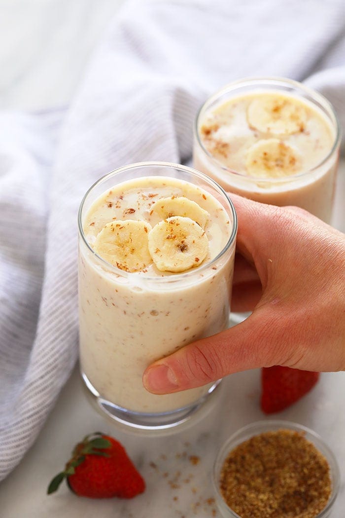 A hand holding a banana smoothie