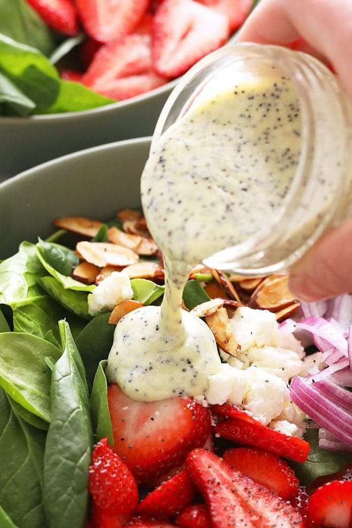 Dressing being poured over salad ingredients. 