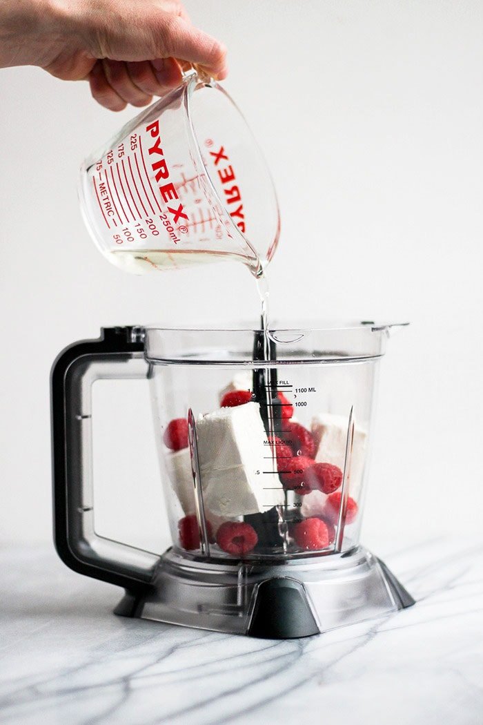 pouring coconut oil into food processor 