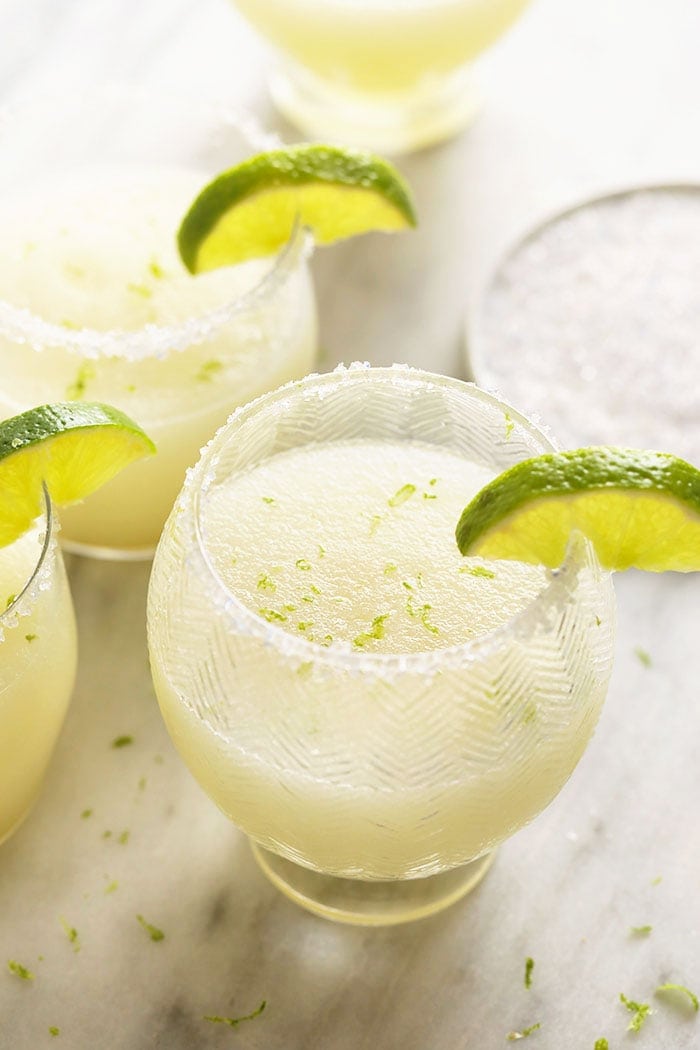 Frozen Margaritas in glasses with limes.