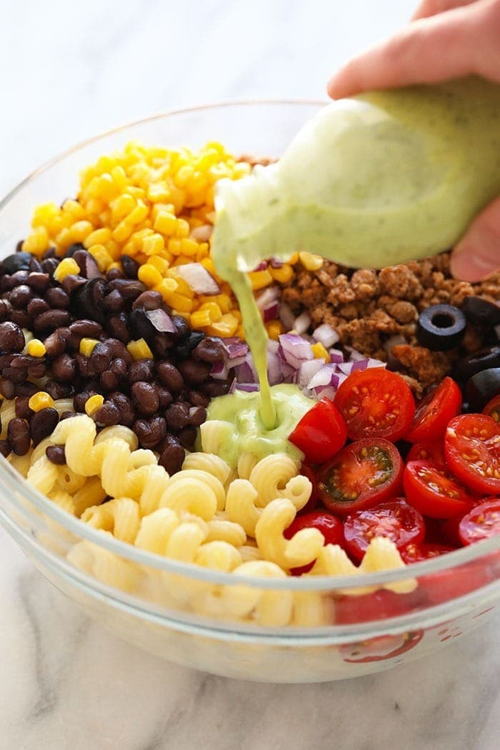 Pouring salad dressing on a salad