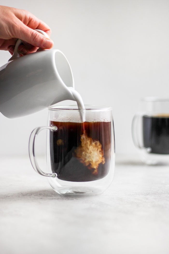 Pouring cream into a cup of coffee.