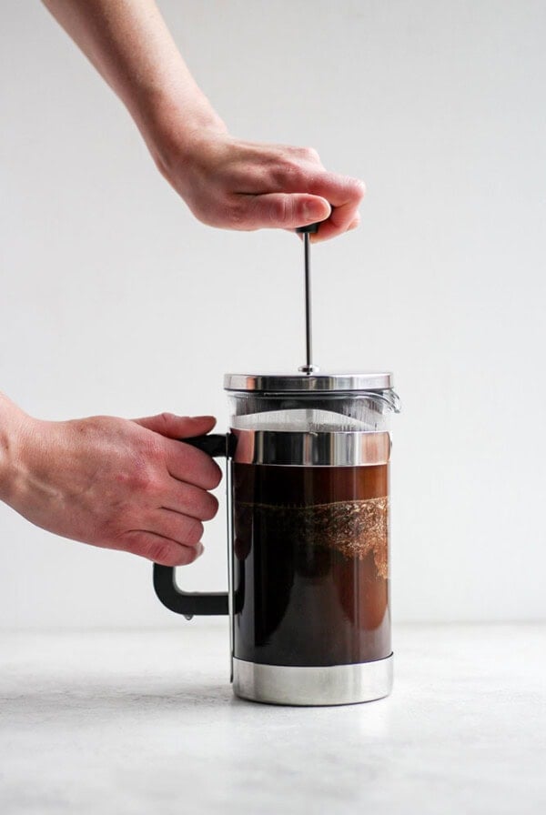 A person using a French press to pour coffee.