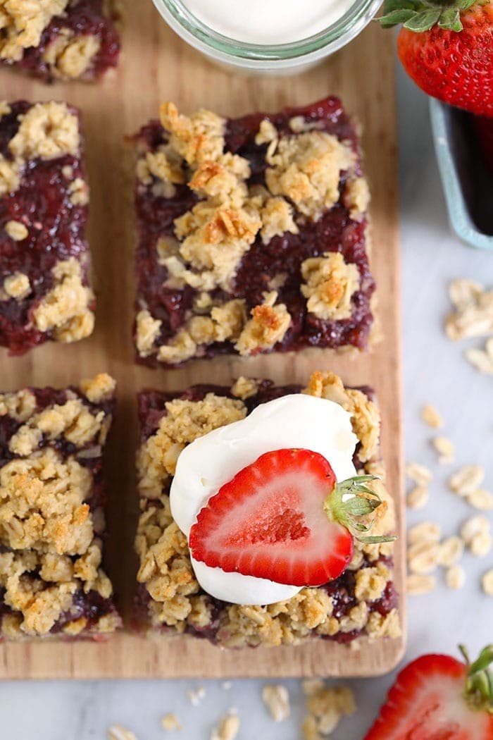 sliced strawberry oatmeal bars topped with whipped cream and a fresh strawberry