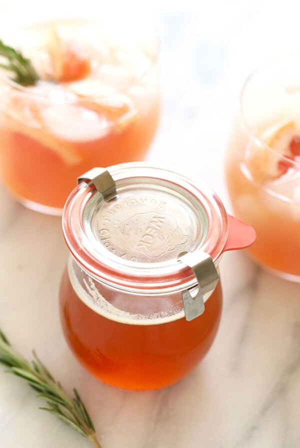 A jar of honey infused with a sprig of rosemary.