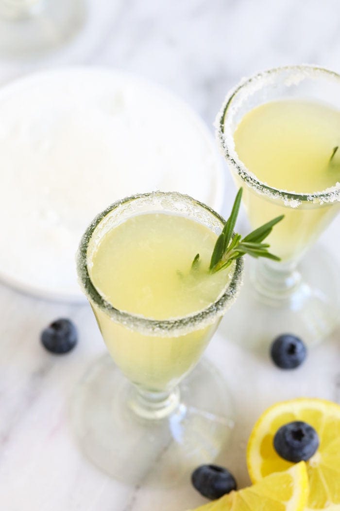 lemon drop martini in a glass with rosemary garnish