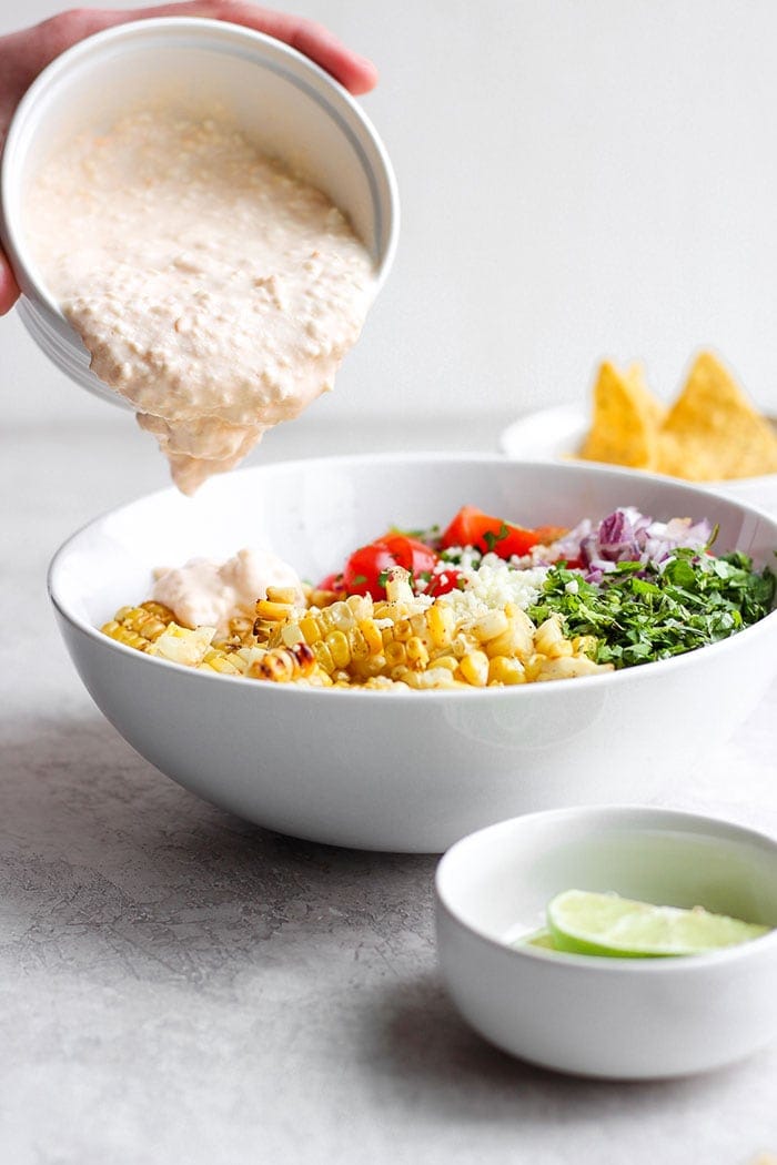 Pouring sauce onto the Mexican Street Corn Salad.