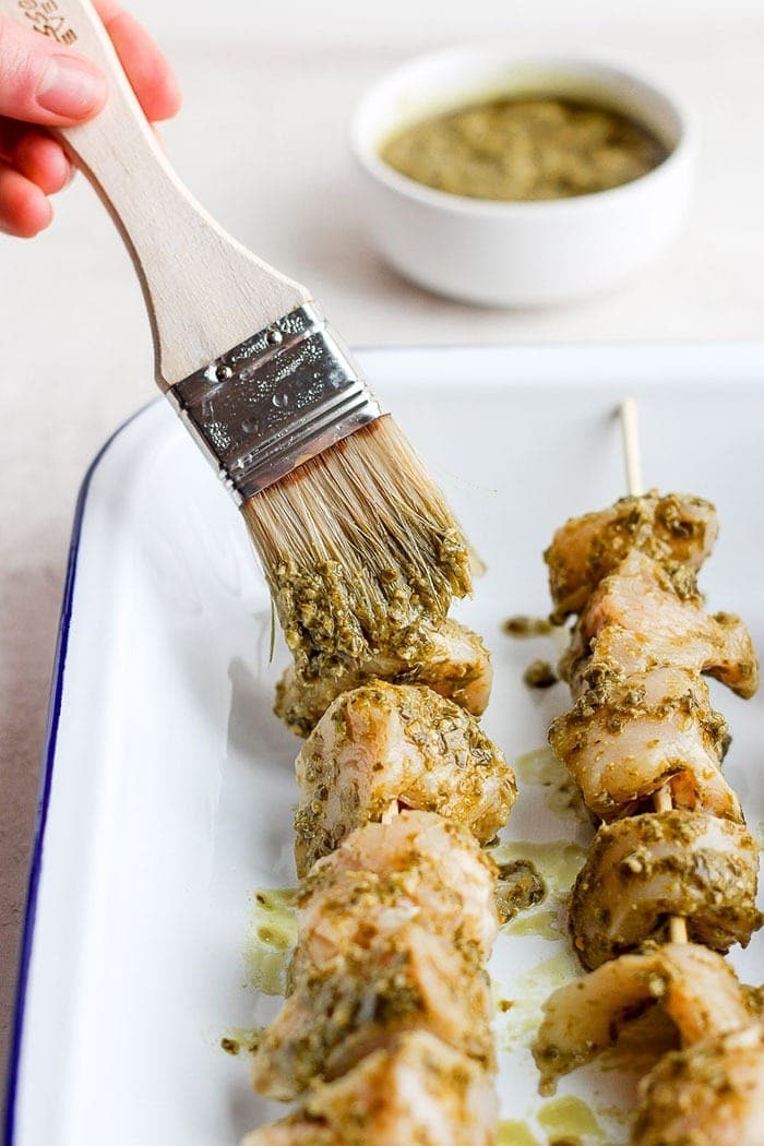 wiping pesto onto chicken skewers.