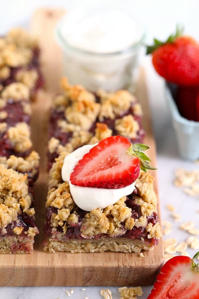 strawberry oatmeal bars sliced on a cutting board and topped with a strawberry