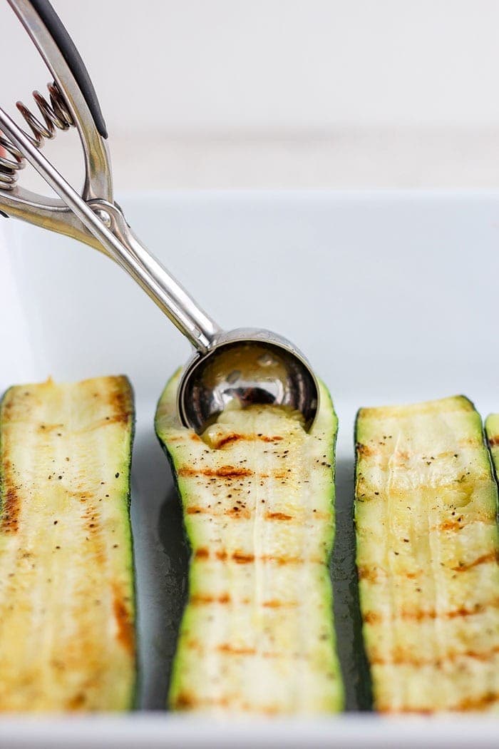 sliced zucchini being scooped with a melon baller