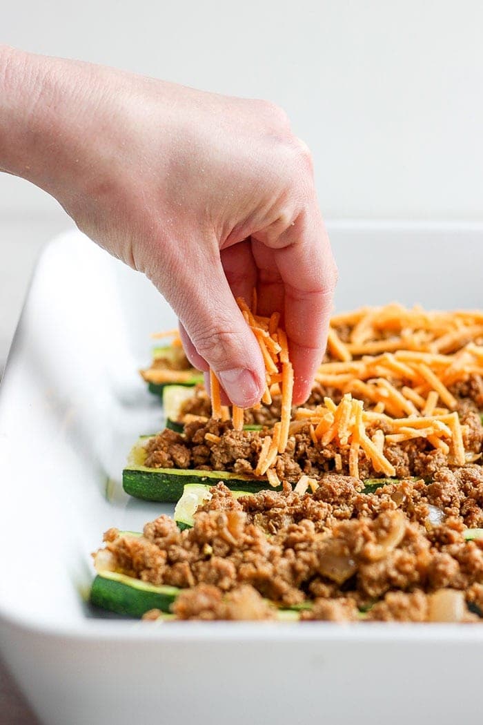 taco zucchini boats being sprinkled with cheese