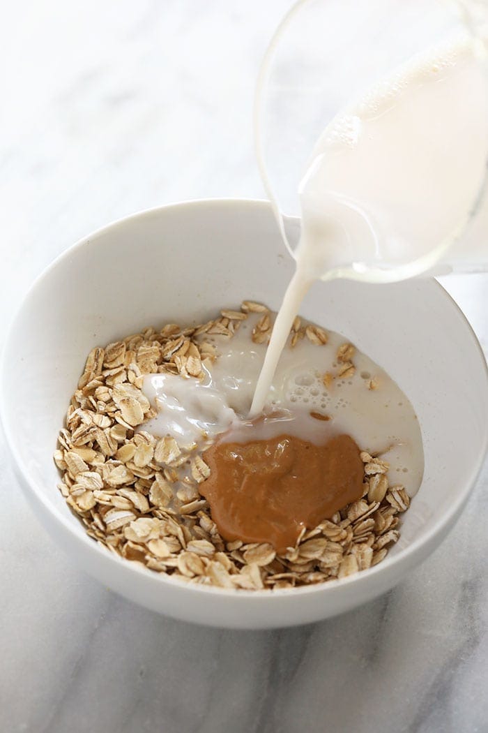 adding milk to oatmeal in bowl