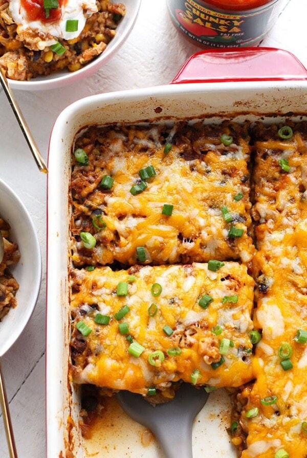 Mexican chicken casserole layered with sour cream and cheese in a baking dish.