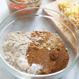 The ingredients for apple cinnamon pancakes are in a bowl next to a measuring cup with bread.