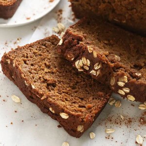 A slice of pumpkin bread with cinnamon and oats on a white plate.