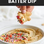 A person is dipping a cookie into a bowl of delicious Cake Batter Dip.