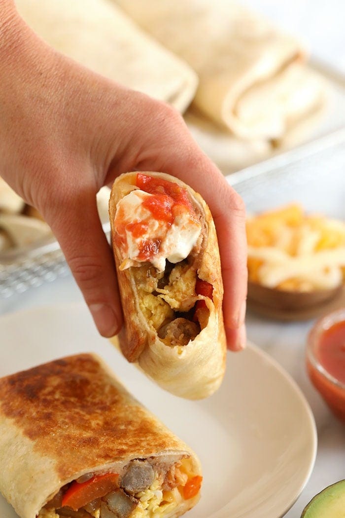 A hand holding fajita breakfast burritos