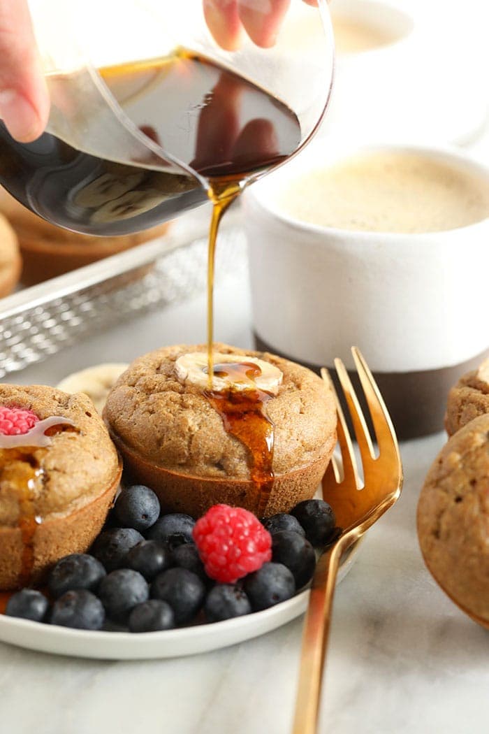 banana pancake muffins being drizzled with maple syrup