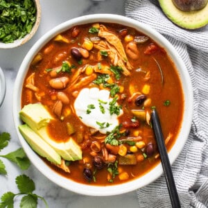 A bowl of chicken enchilada soup with avocado and sour cream.