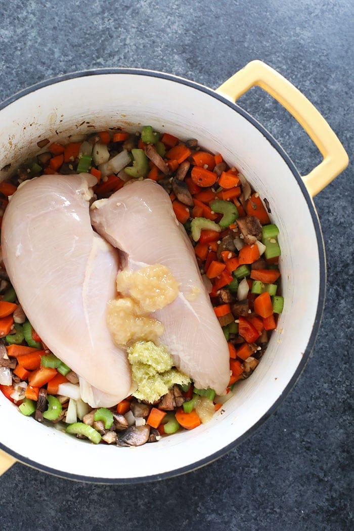 chicken noodle soup with chicken and veggies in a pot ready to be cooked