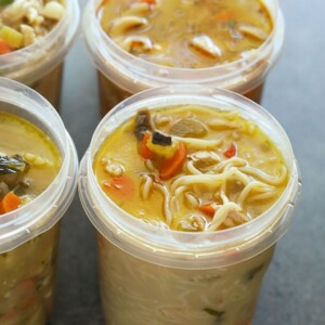 Four plastic containers filled with soup are frozen.