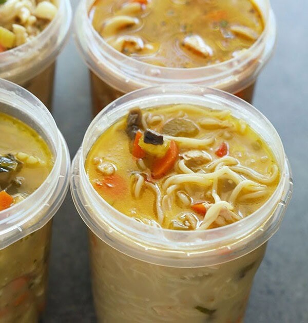 Four plastic containers filled with soup are frozen.