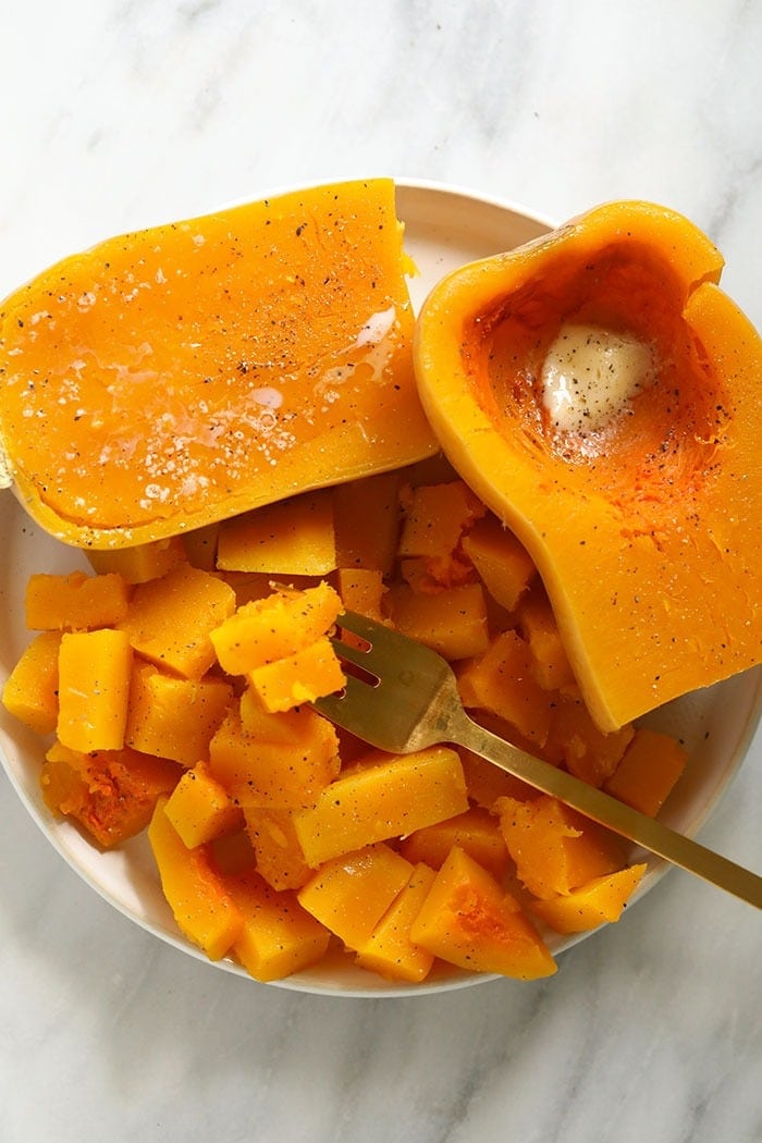 cooked butternut squash on a plate with butter, salt, and pepper