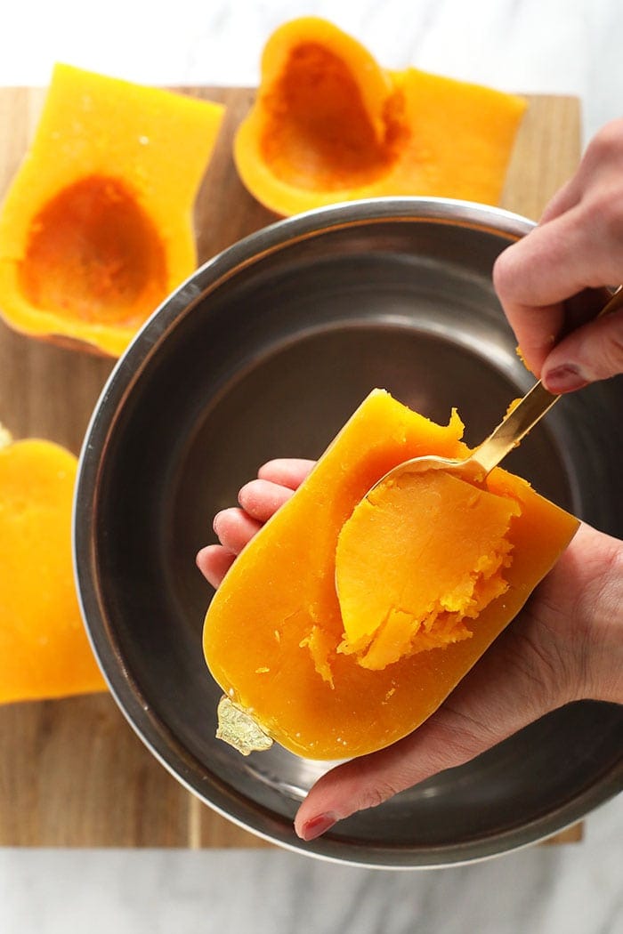 scooping out the butternut squash meat from the roasted butternut squash