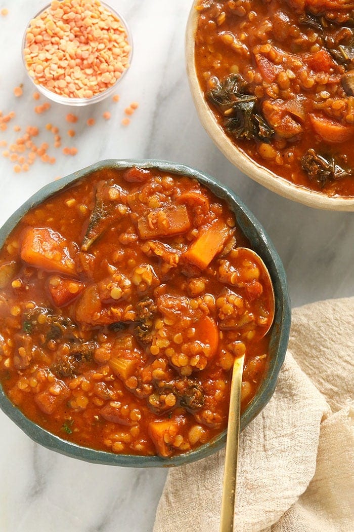 A bowl of lentil stew with a spoon in it. 