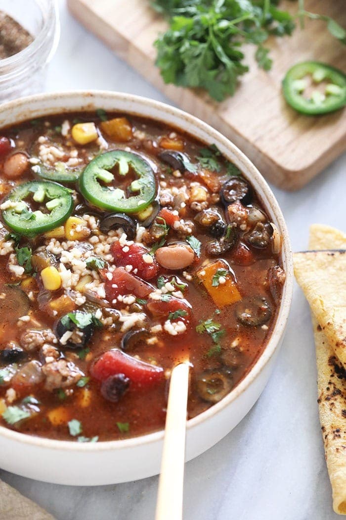 slow cooker taco soup in a bowl topped with cotija and jalapenos