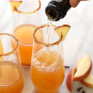 Thanksgiving cocktails featuring a bottle of apple cider being poured into a glass.