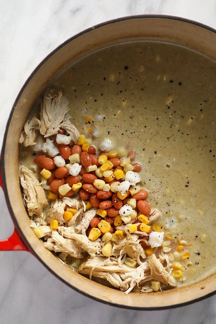 white bean chicken chili ingredients in a dutch oven ready to be stirred together.