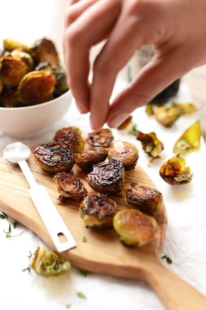 roasted brussel sprouts being sprinkled with sea salt