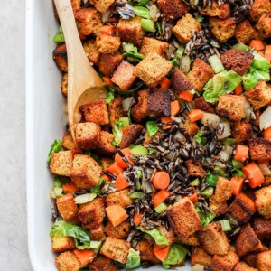 A dish of cornbread dressing with carrots and brussels sprouts.