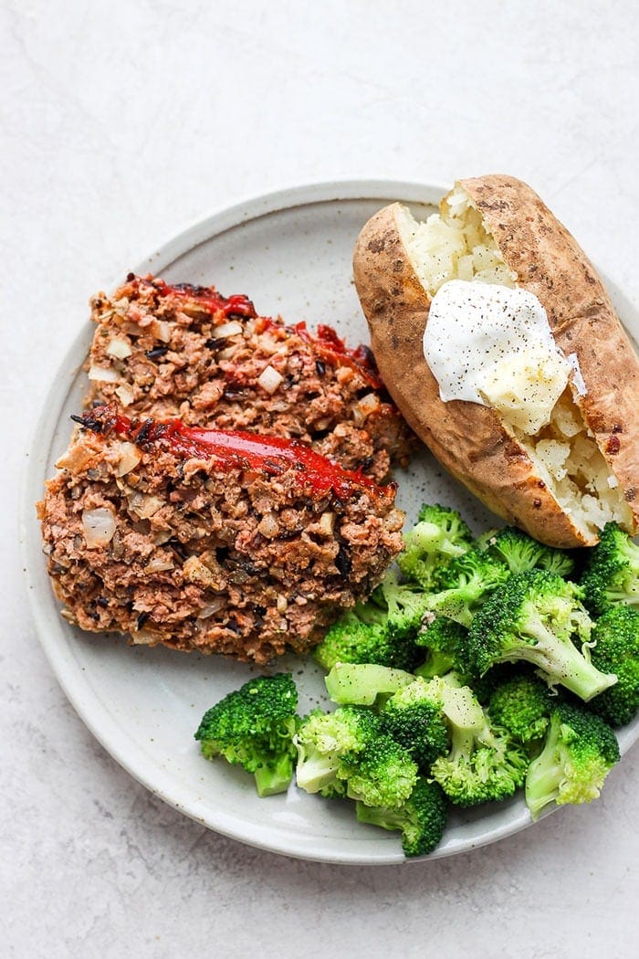 wild rice meatloaf on a plate with a baked potato and broccoli