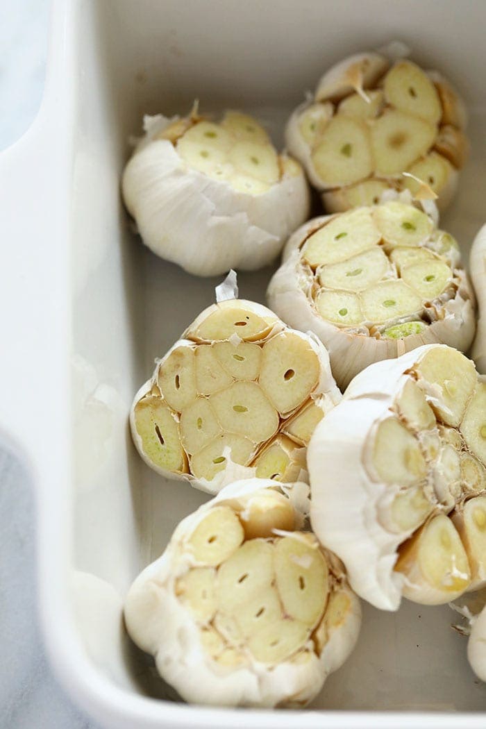 fresh garlic bulbs ready to be roasted in a baking dish