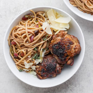 Two bowls of chicken pasta topped with parmesan.