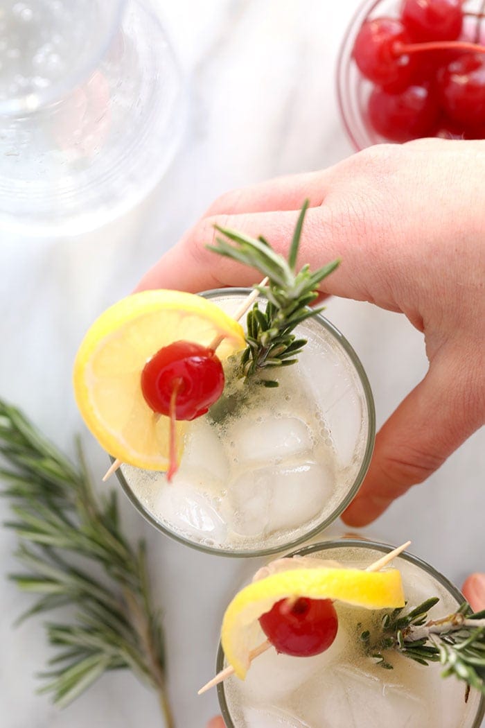 rosemary collins in a glass garnished with a sprig of rosemary 